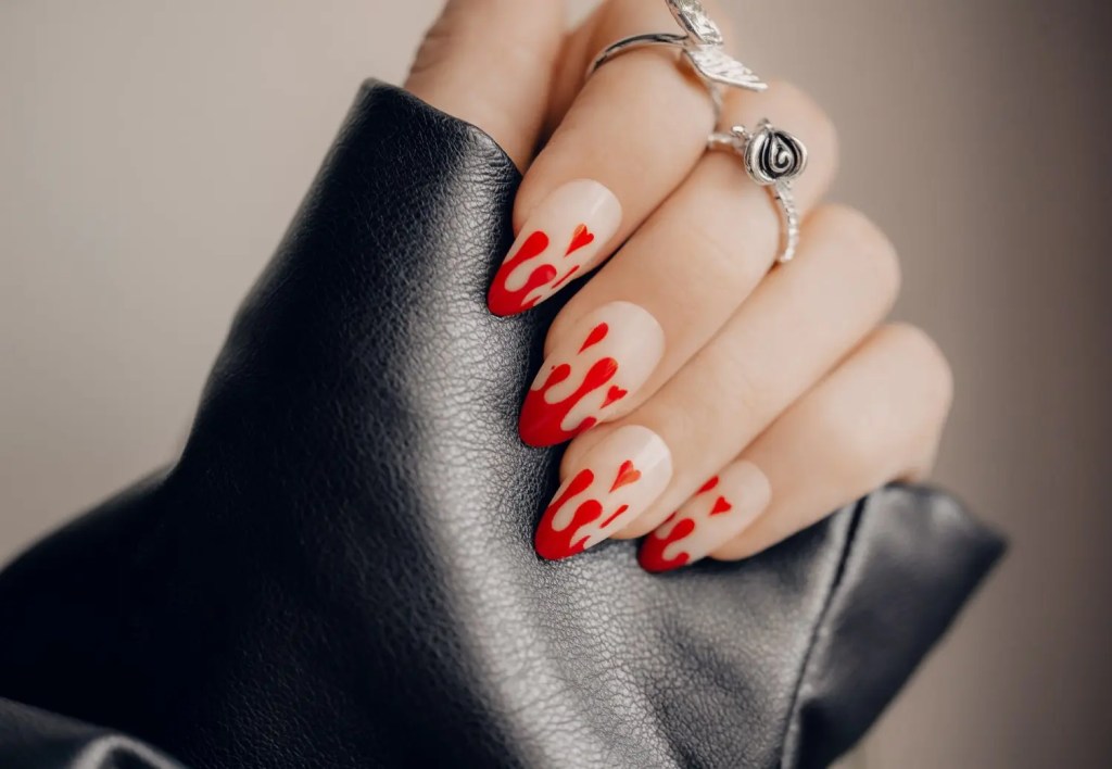 Mão de uma pessoa branca, com destaque para as unhas decoradas com nail art de sangue.