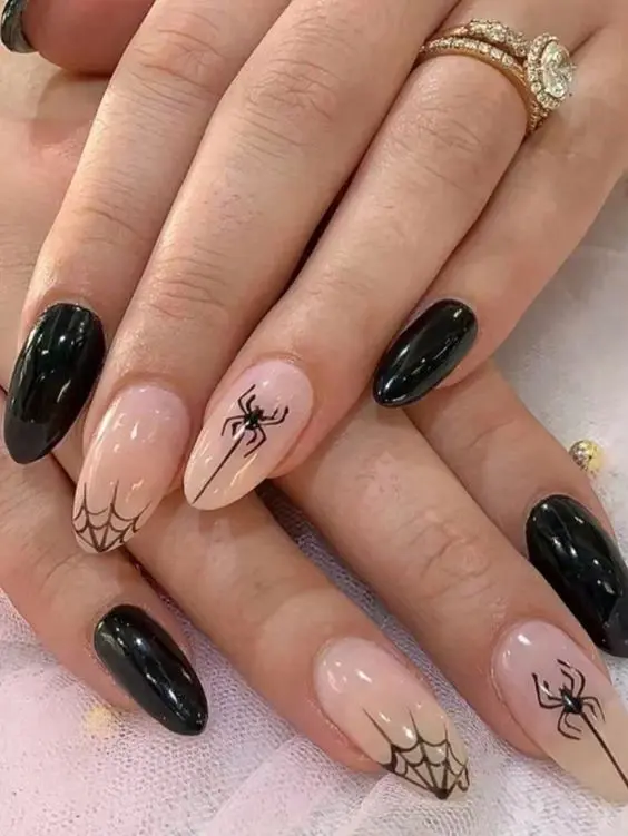 Mãos de uma pessoa branca, com destaque para suas unhas, decoradas com aranhas e teias.